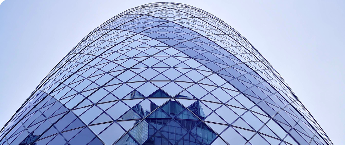 Close-up of a modern glass office building with a curved fa&ccedil;ade and geometric pattern.