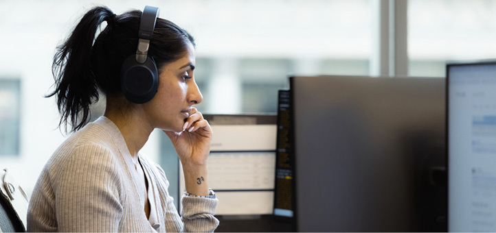 Employee working at a computer with headphones on at the New York office.