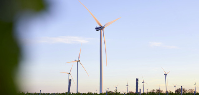 Wind turbines generating renewable energy in a wind farm at sunset.