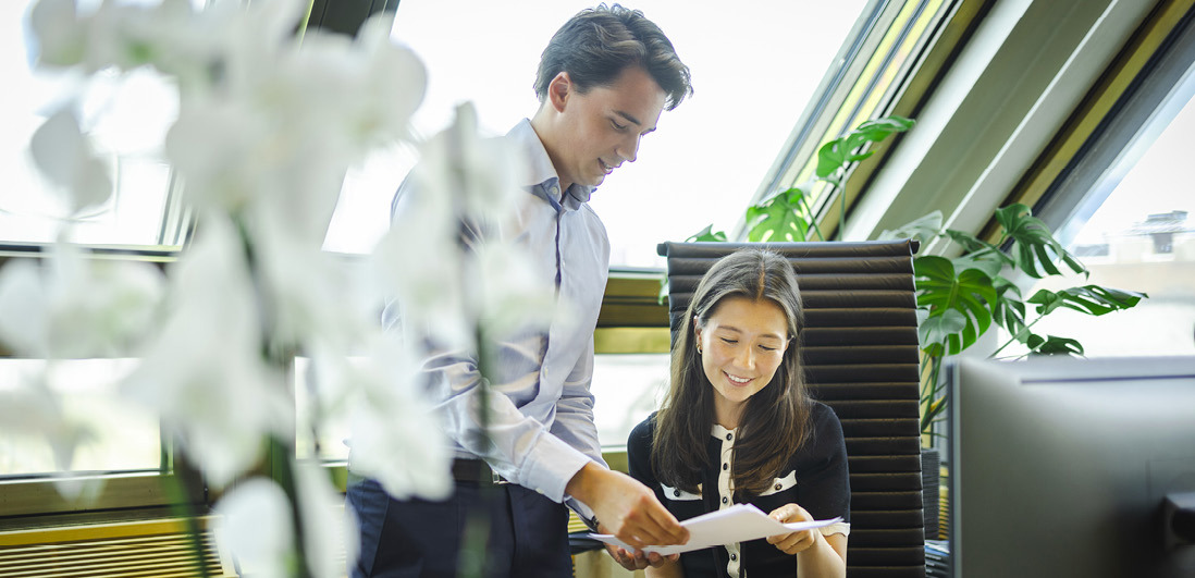 To ansatte i samtale ved skrivebord på Oslo-kontoret.