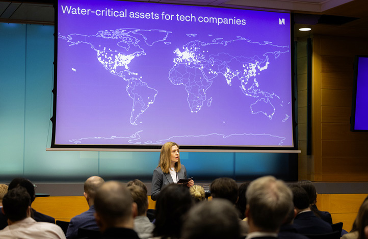 Presenter speaking in front of a slide titled “Water-critical assets for tech companies,” showing a world map with highlighted locations.