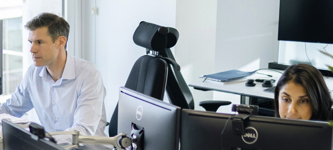 Two employees working at computer monitors in an office.
