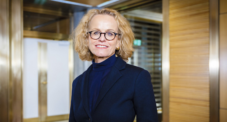 A woman wearing a blue shirt and black jacket stands in front of a door.

AI generated content